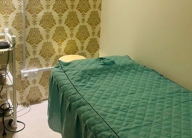 Cozy spa room at Pixi Dust, Kuala Lumpur, with green bedding and golden wallpaper, offering a calming retreat.