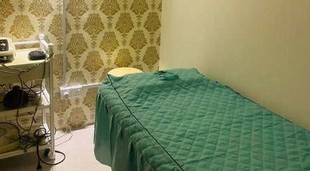 Cozy spa room at Pixi Dust, Kuala Lumpur, with green bedding and golden wallpaper, offering a calming retreat.