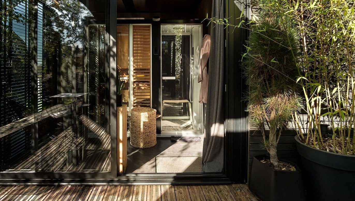 Entrée vitrée de Le Cube Massages & Spa à Jouey, Bourgogne-franche-comté, FR, entourée de verdure.