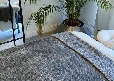 Serene massage room at Waseley Wellbeing in Worcestershire, GB with cosy bedding and calming decor.