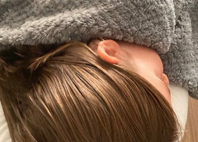 Person relaxing under a cozy gray blanket at Waseley Wellbeing, Worcestershire, GB, offering tranquility and comfort.