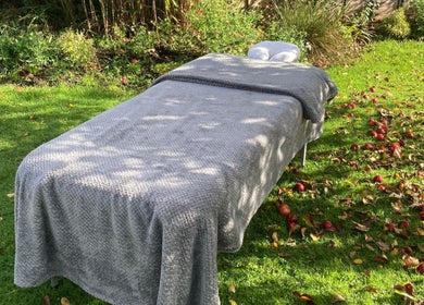 Outdoor massage table at Waseley Wellbeing, Worcestershire, GB amidst lush greenery and fallen apples.