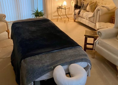 Cozy massage room at Waseley Wellbeing, Worcestershire, GB, featuring a plush table and soft lighting.