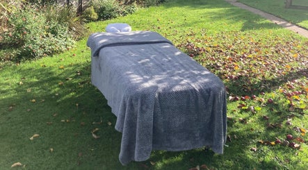 Outdoor massage table at Waseley Wellbeing, Worcestershire, GB, surrounded by lush greenery.