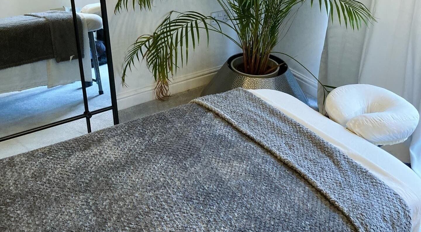 Relaxing massage room at Waseley Wellbeing, Worcestershire, GB, featuring a cozy treatment table and lush plant.