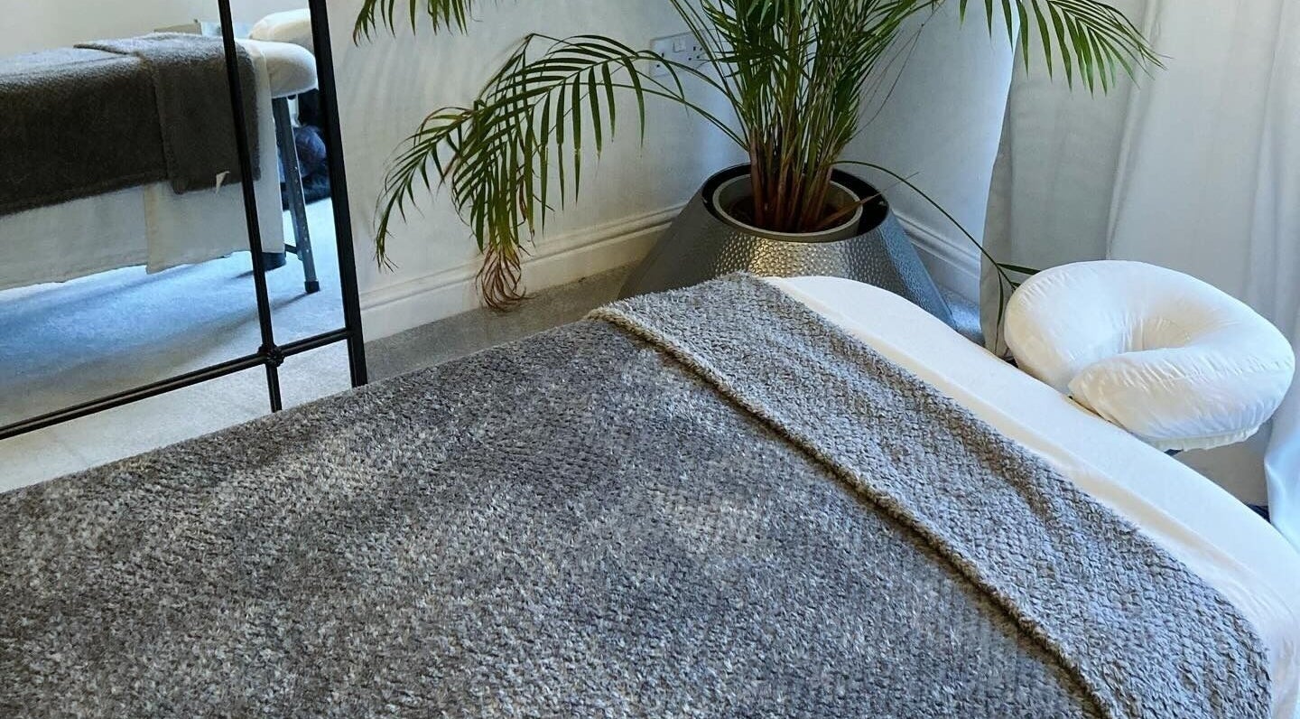 Relaxing massage room at Waseley Wellbeing, Worcestershire, GB, featuring a cozy treatment table and lush plant.