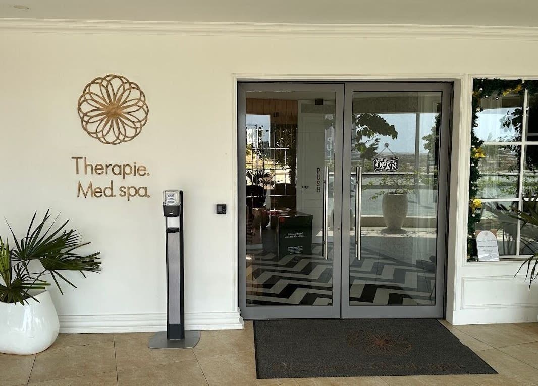 Entrance of Therapie Medspa in Lagos, Lagos, NG with elegant glass doors and greenery.