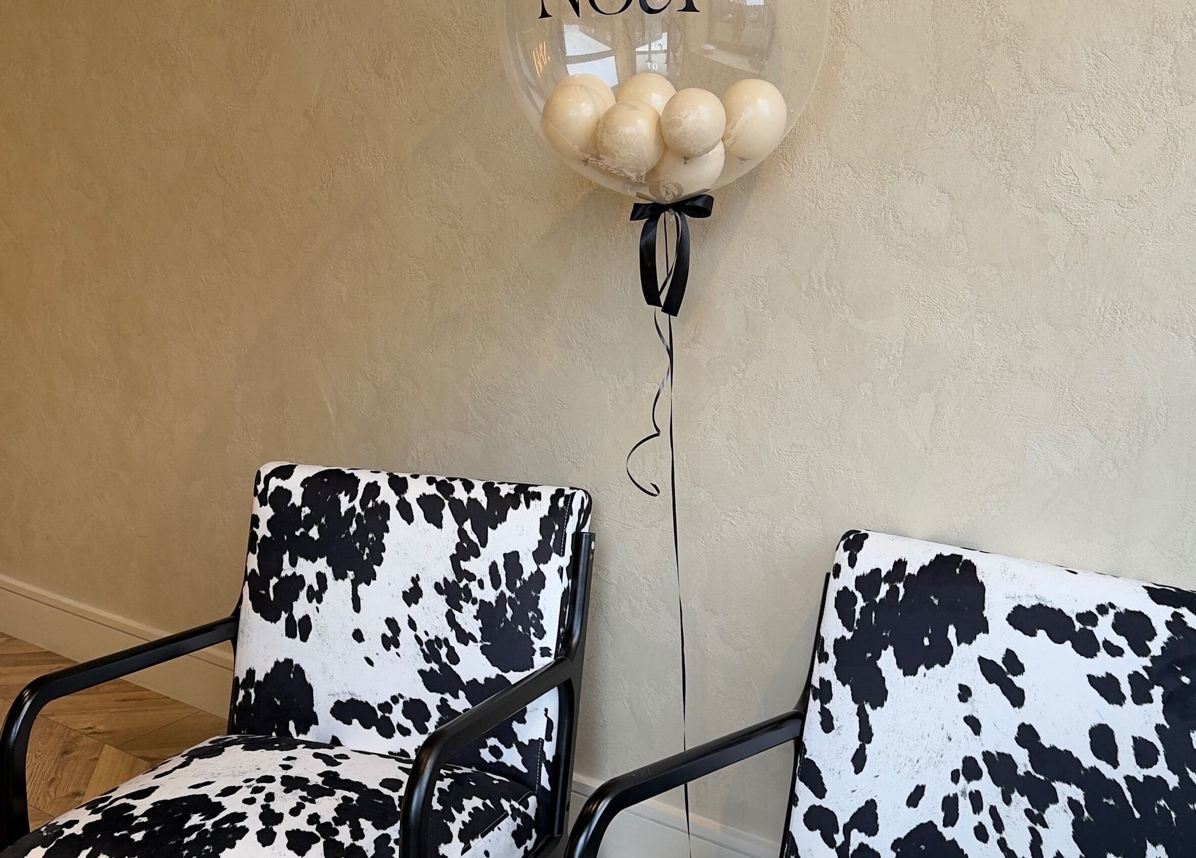 Stylish cowhide chairs and neutral decor at TATTOOBAE in Bury, England, GB create a chic, inviting ambiance.