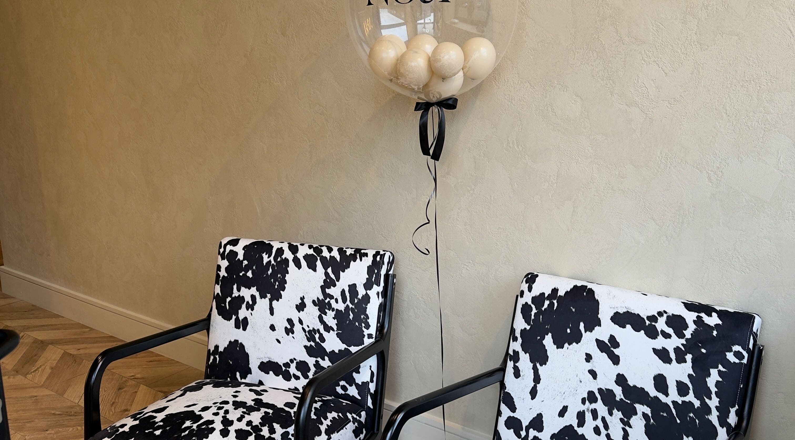 Stylish cowhide chairs and neutral decor at TATTOOBAE in Bury, England, GB create a chic, inviting ambiance.