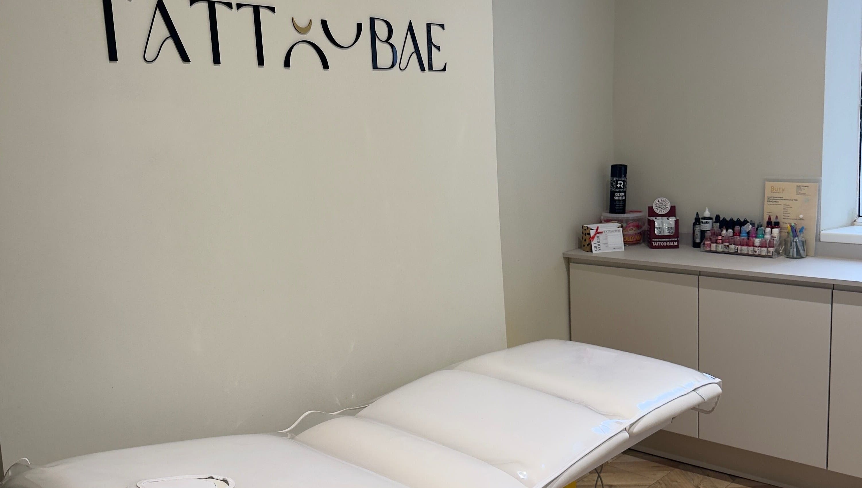 Tattoo station at TATTOOBAE in Bury, England, GB, featuring a white table and ink supplies.