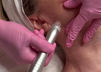 Facial treatment at Skinrise, London, England, GB. Pink-gloved hands using skincare device on client's face.
