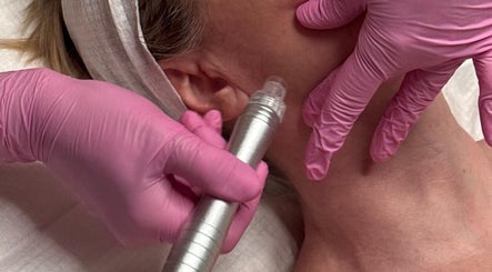 Facial treatment at Skinrise, London, England, GB. Pink-gloved hands using skincare device on client's face.