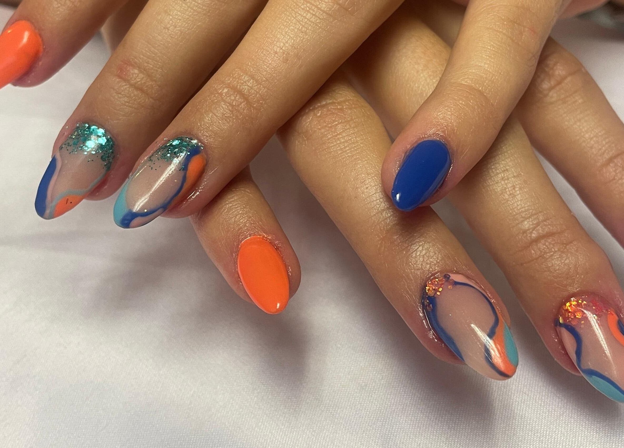 Colorful nail art at Cat's Claw Nails in Pretoria, Gauteng, ZA showcasing vibrant blue and orange designs.