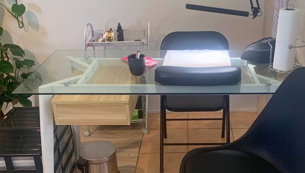Modern nail station at MooMooCat Nails, Auckland, NZ, featuring a glass table and lush greenery.