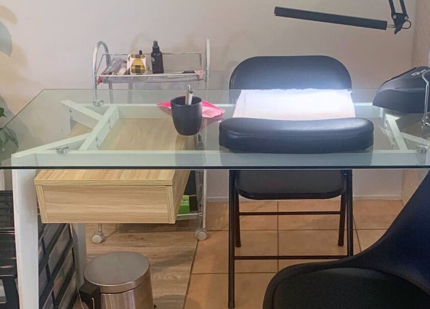 Modern nail station at MooMooCat Nails, Auckland, NZ, featuring a glass table and lush greenery.