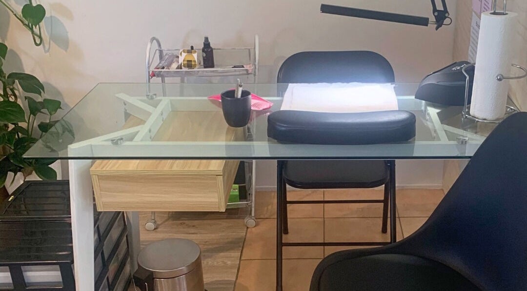 Modern nail station at MooMooCat Nails, Auckland, NZ, featuring a glass table and lush greenery.