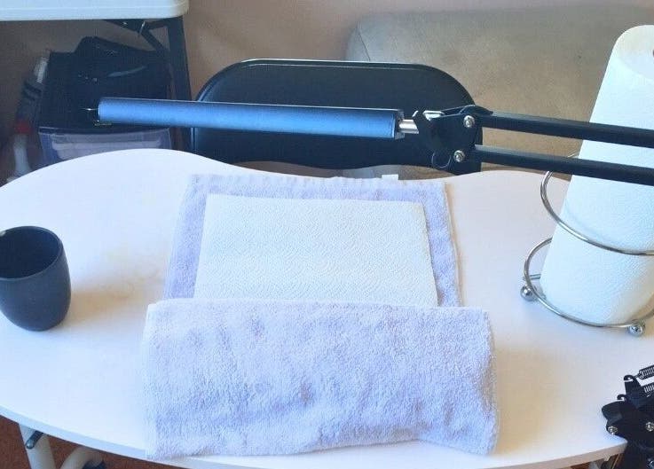 Organized nail station at MooMooCat Nails, Auckland, NZ, featuring towels and a lamp.