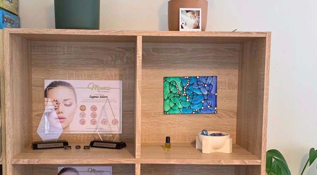 Elegant shelf display at MooMooCat Nails in Auckland, NZ, featuring awards and colorful art piece.