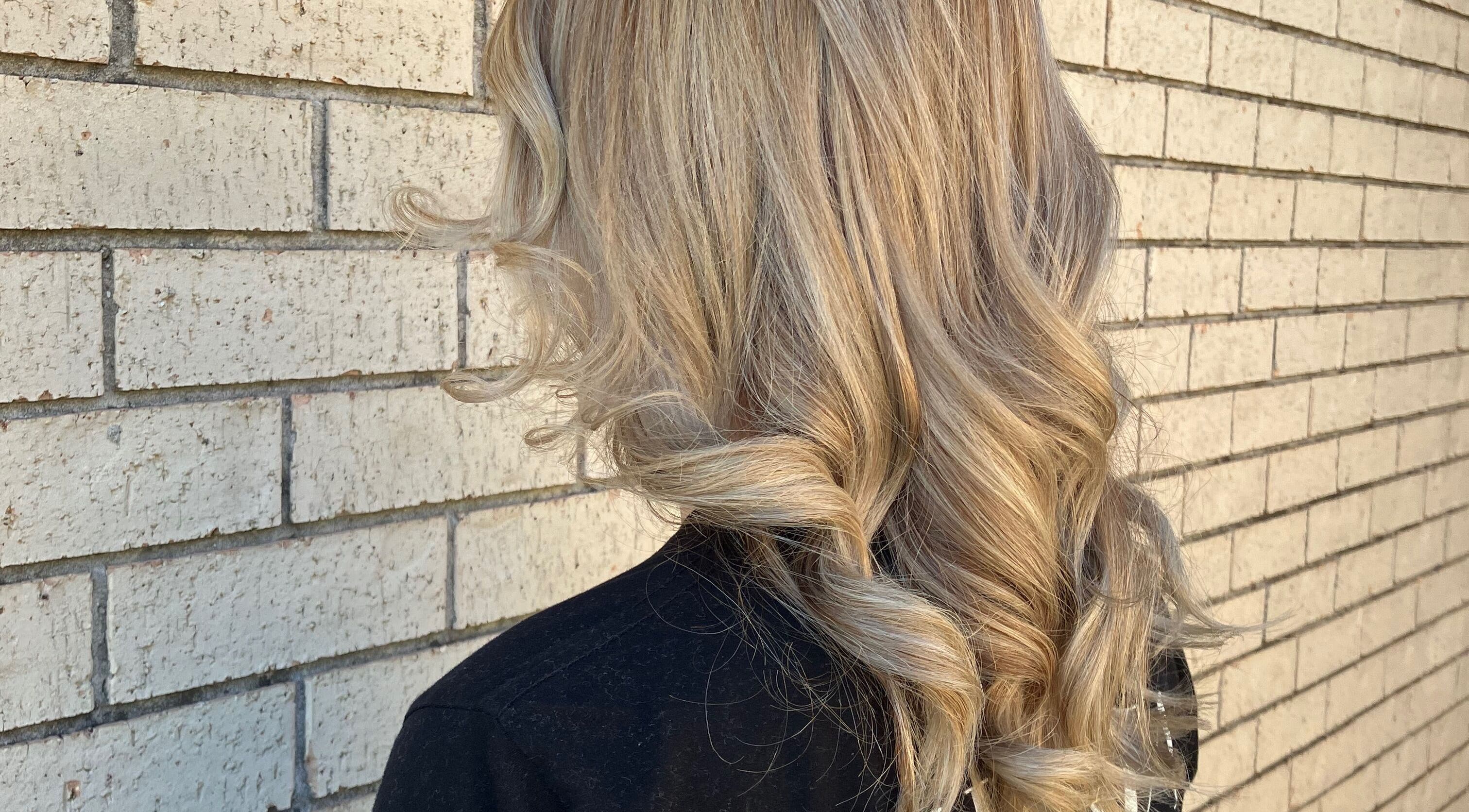 Blonde waves styled at Sammy Hair in Thornton, New South Wales, AU against a textured brick wall.