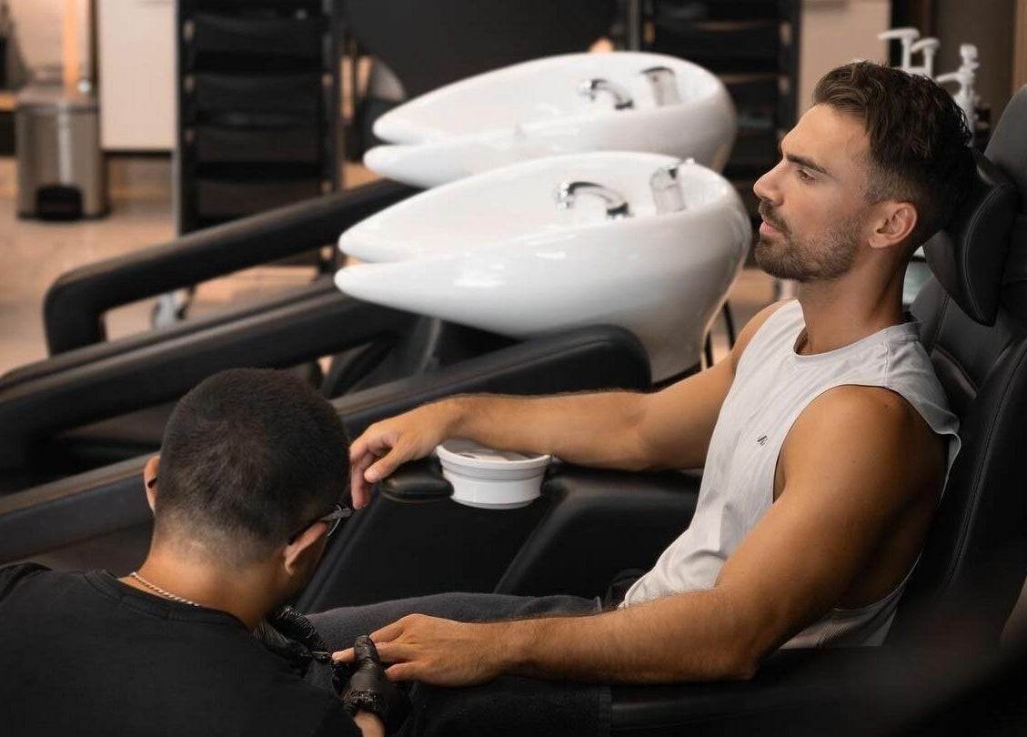 Man enjoying a manicure at Barbero Gentlemen's Lounge 2 in Dubai, AE with modern salon chairs and sinks.