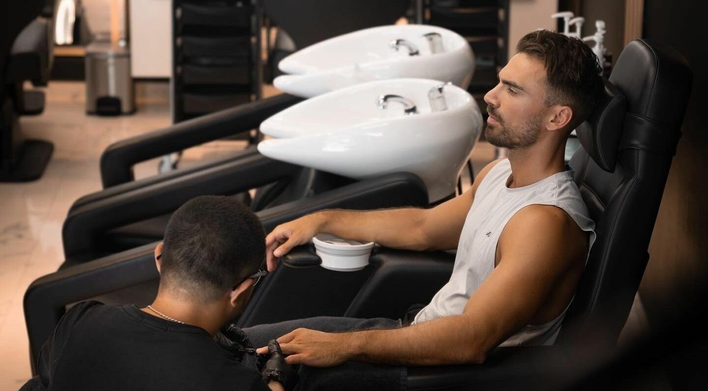 Man enjoying a manicure at Barbero Gentlemen's Lounge 2 in Dubai, AE with modern salon chairs and sinks.