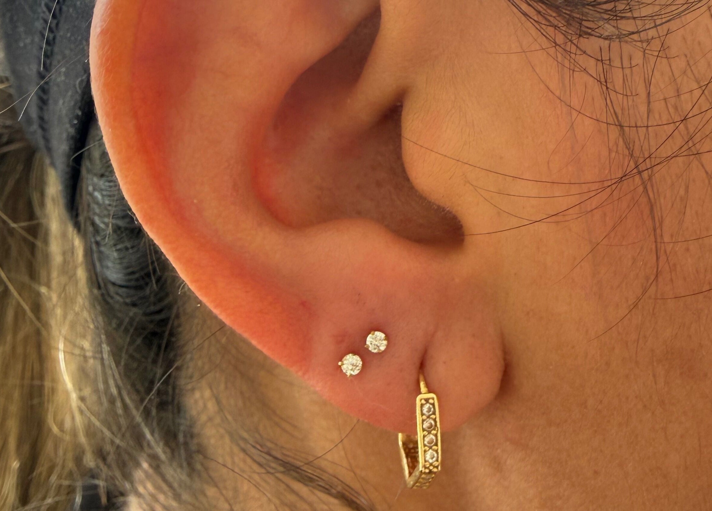 Close-up of elegant piercings at Pierce’T, Curaçao, Curaçao, CW showcasing diamond studs and gold hoops.