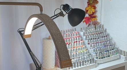 Nail polish display at Luxe Beauty by Rosie, Lowestoft. Elegant lamp and autumn decor create a cozy ambiance.
