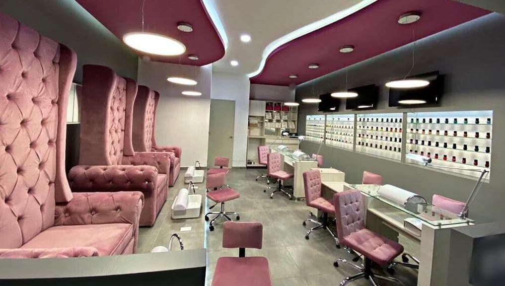 Interior de Bespoke Nails and Spa en Santiago De Querétaro, con sillas rosas y mesas de manicure.