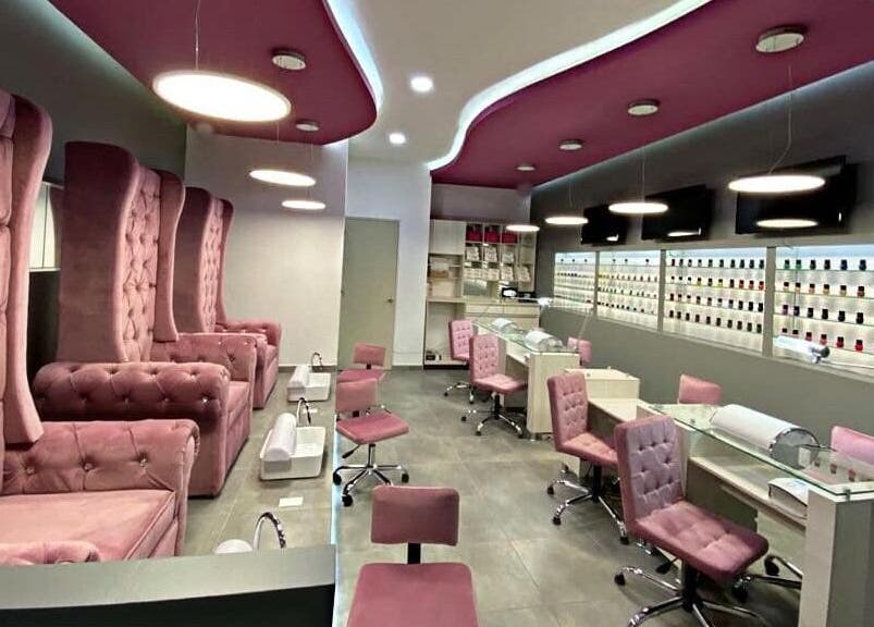 Interior de Bespoke Nails and Spa en Santiago De Querétaro, con sillas rosas y mesas de manicure.