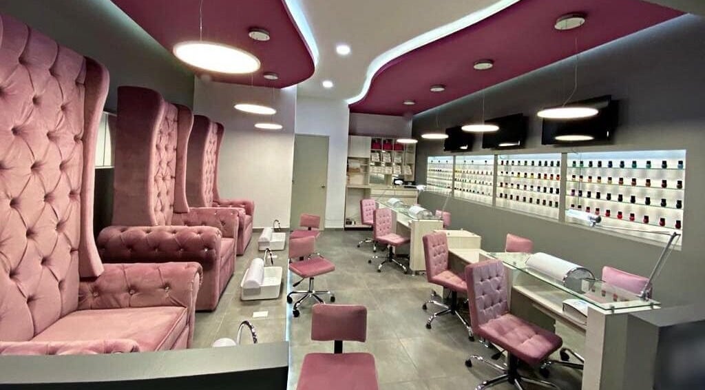 Interior de Bespoke Nails and Spa en Santiago De Querétaro, con sillas rosas y mesas de manicure.
