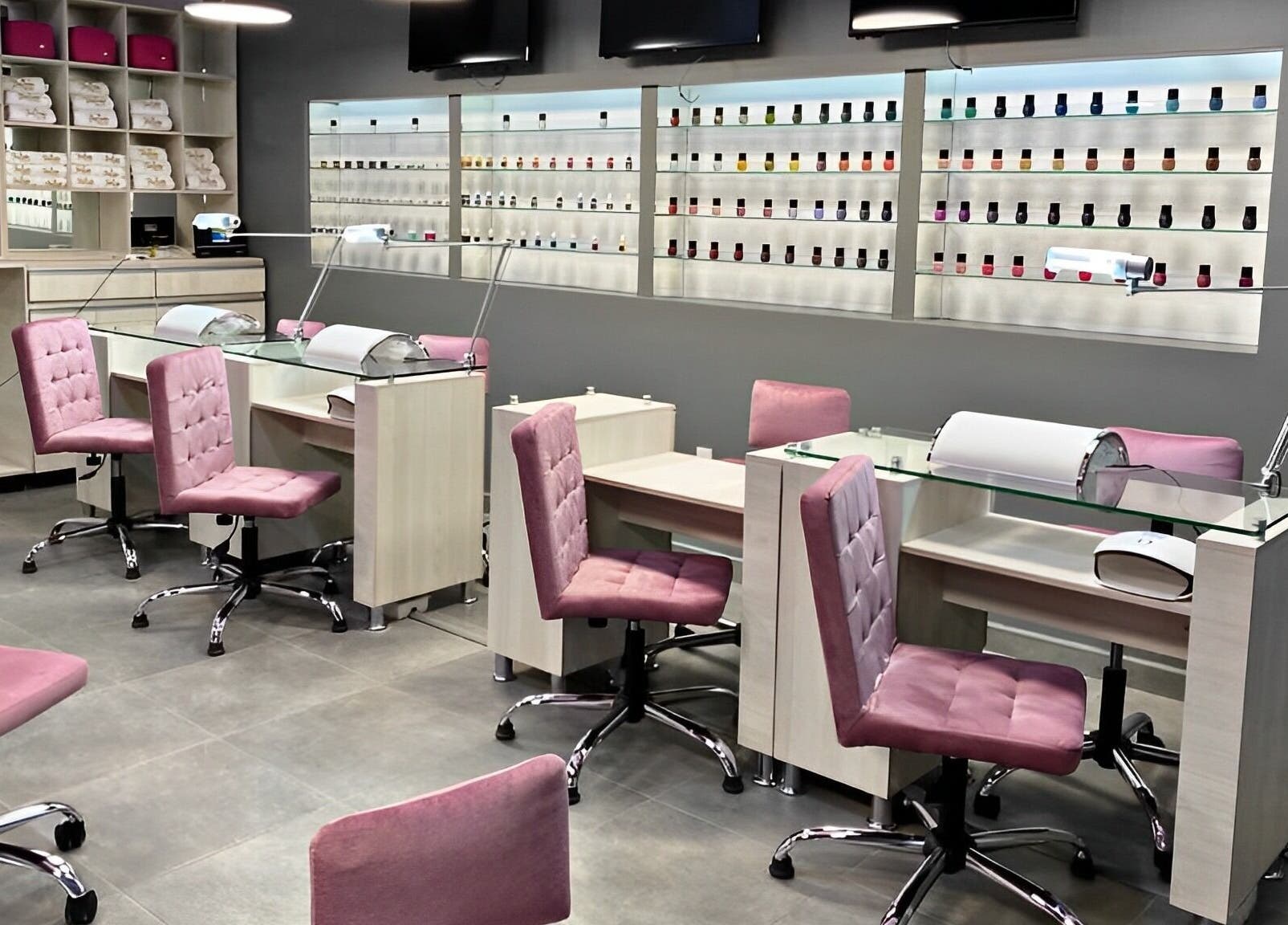 Interior de Bespoke Nails and Spa en Santiago De Querétaro, mostrando elegantes sillas rosadas y estantes de esmaltes.