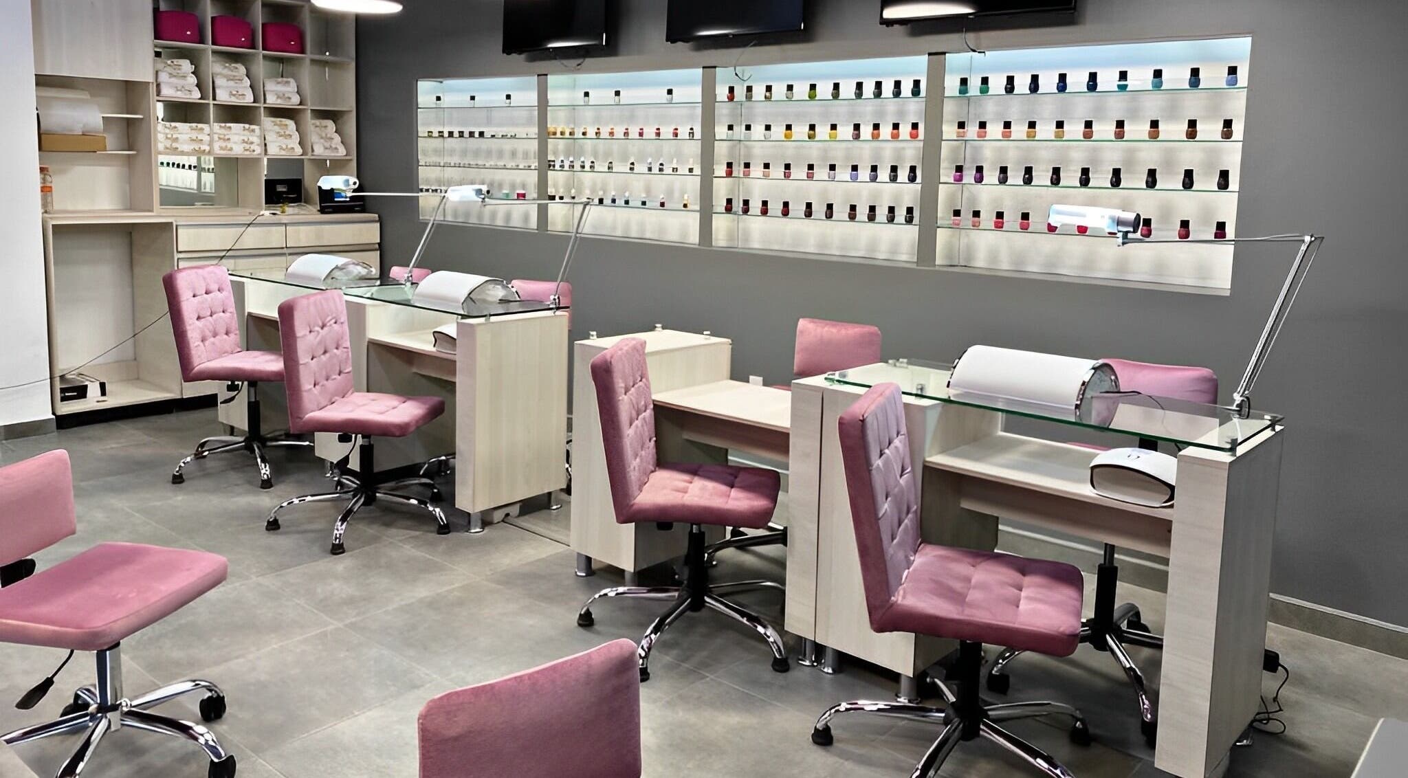 Interior de Bespoke Nails and Spa en Santiago De Querétaro, mostrando elegantes sillas rosadas y estantes de esmaltes.