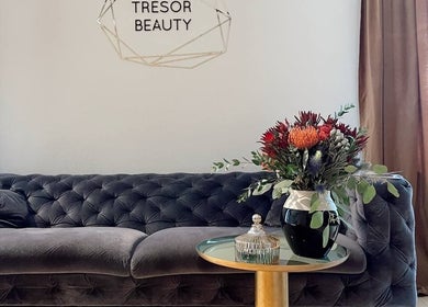 Luxurious seating area at Tresor Beauty in Rīga, LV, featuring a plush sofa and fresh floral arrangement.