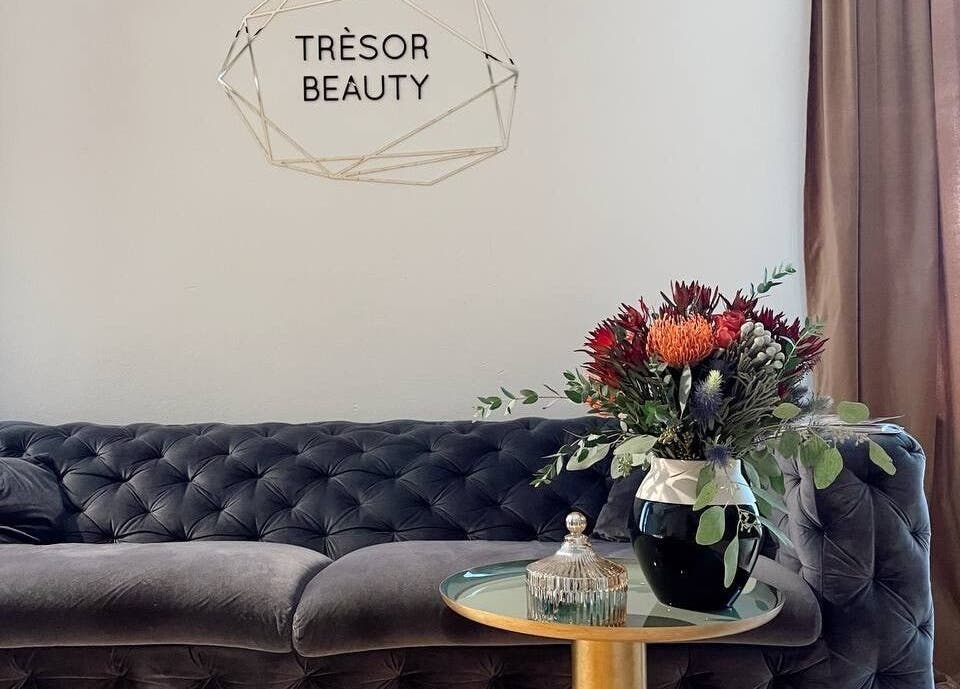 Elegant lounge at Tresor Beauty, Rīga, LV, with floral decor on a plush sofa.
