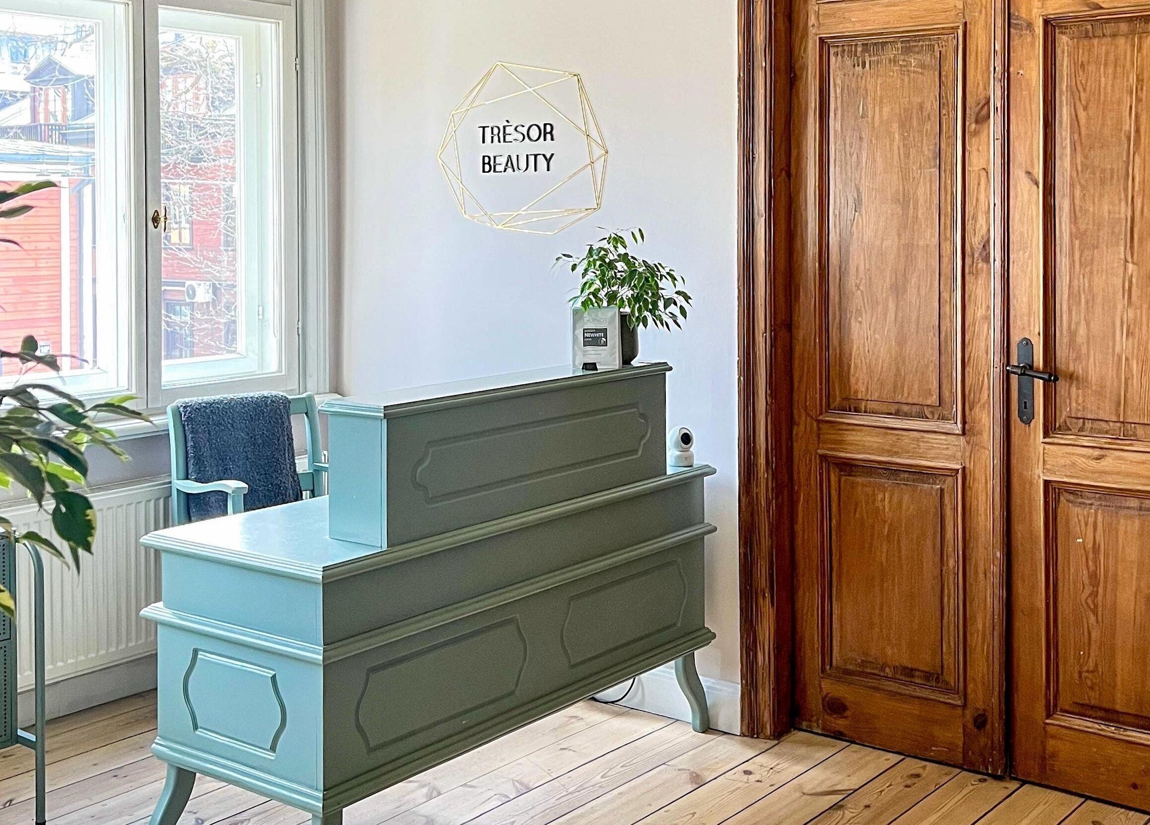 Tresor Beauty's elegant reception area in Rīga, LV featuring a stylish desk and wooden door.