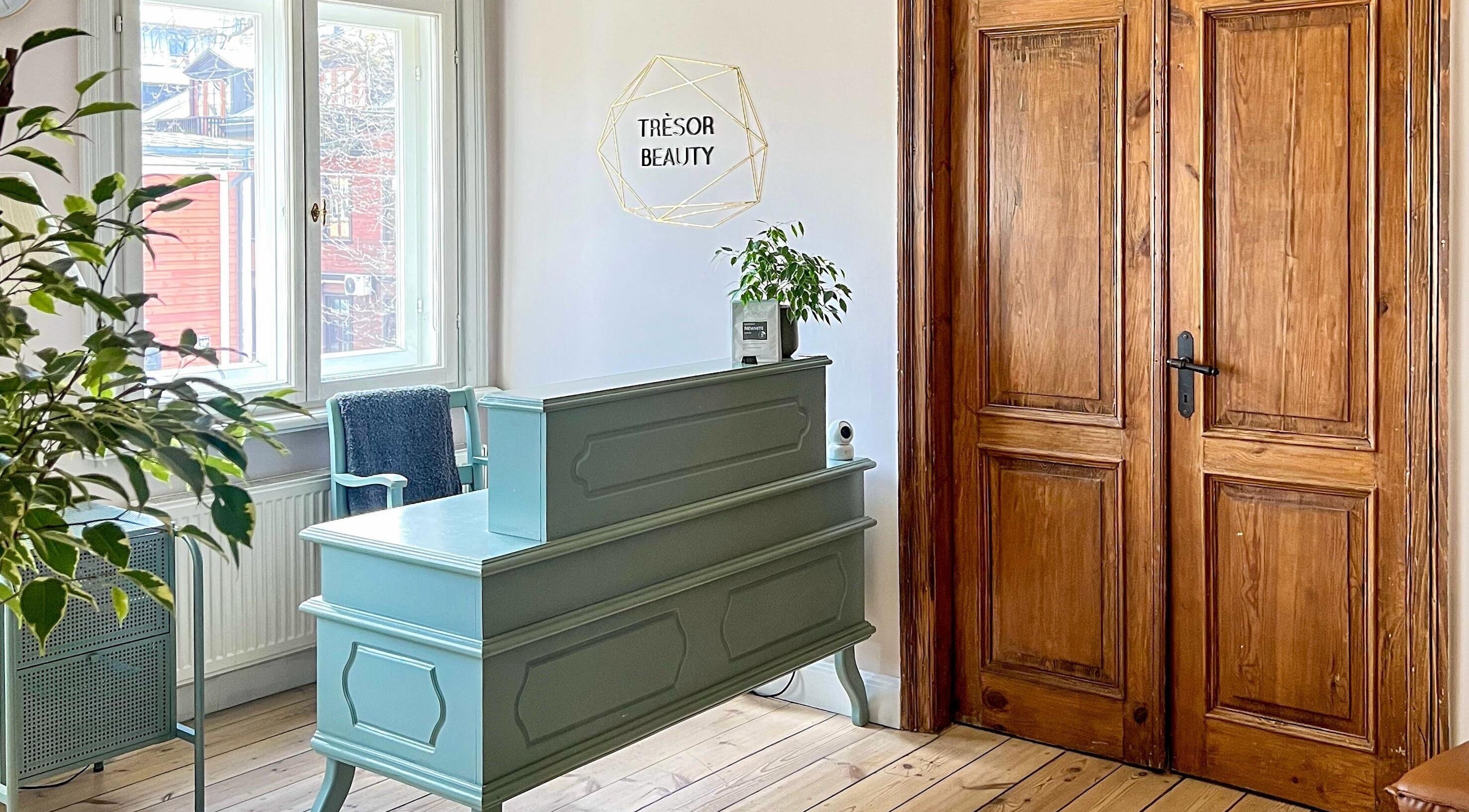 Reception area at Tresor Beauty, Rīga, LV with wooden decor and stylish greenery.