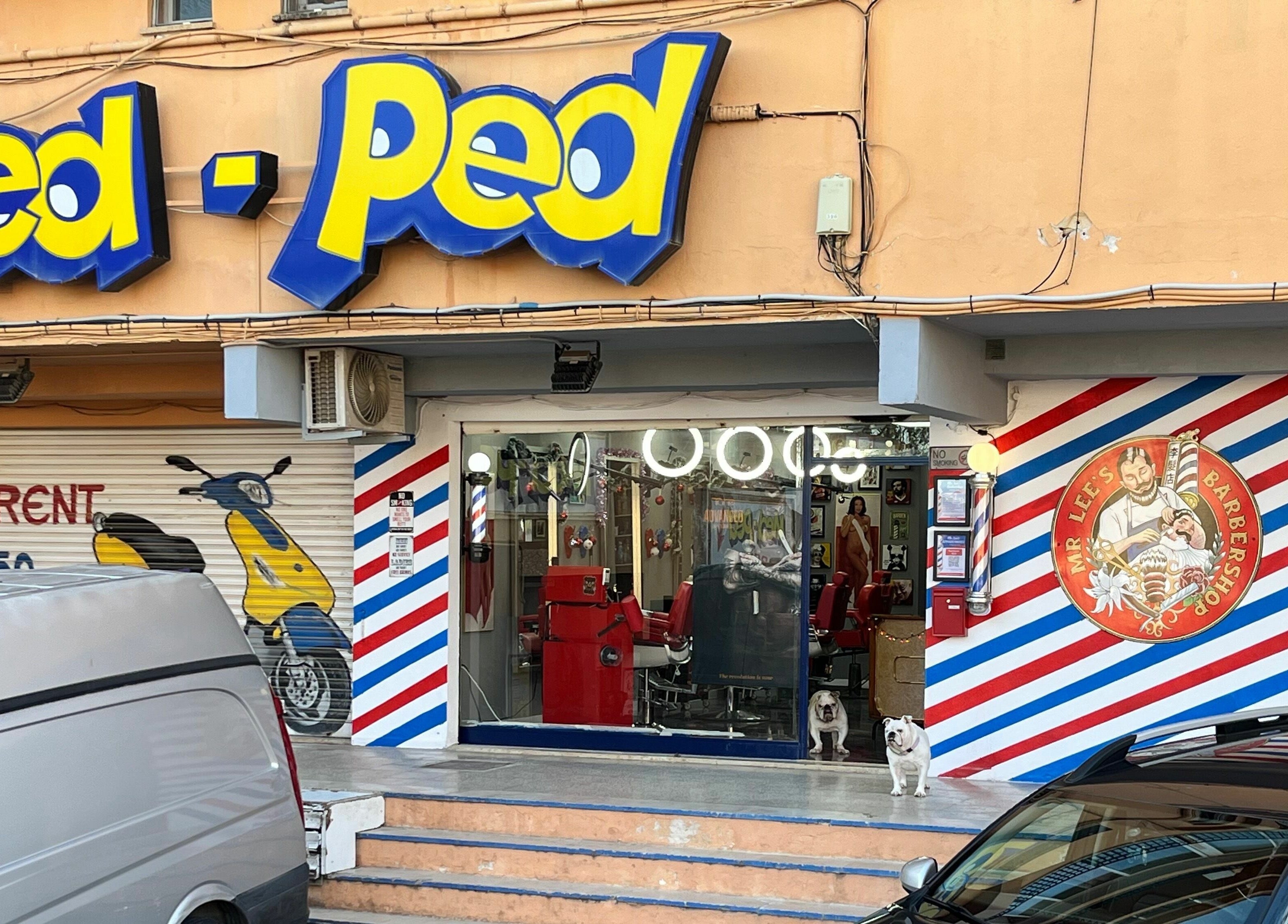 Entrance of Mr. Lee's Barbershop in Magaluf, Illes Balears, ES with red chairs visible inside.