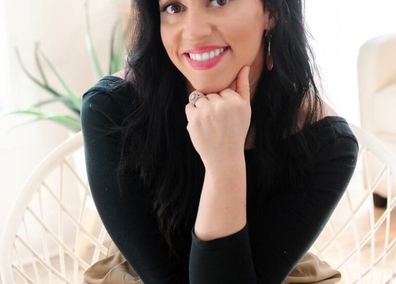 Smiling woman seated at Lashed+ in Norwell, Massachusetts, US, enhancing beauty and wellness experience.