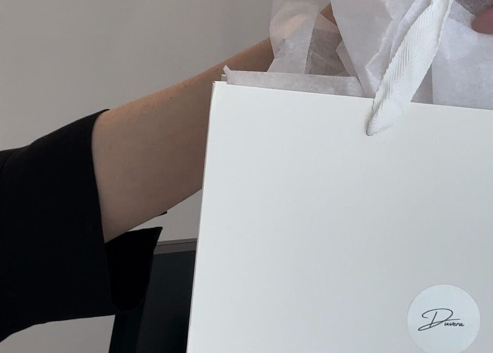 Sac cadeau Duvera à Montréal, Québec, CA, tenu par une main en tenue élégante.