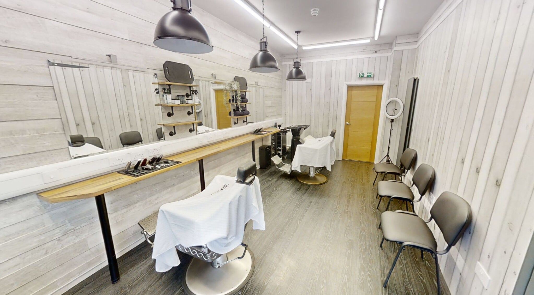 Bright and modern interior of Studio 4 Barbers in Saundersfoot, Wales, GB, featuring stylish barber chairs.