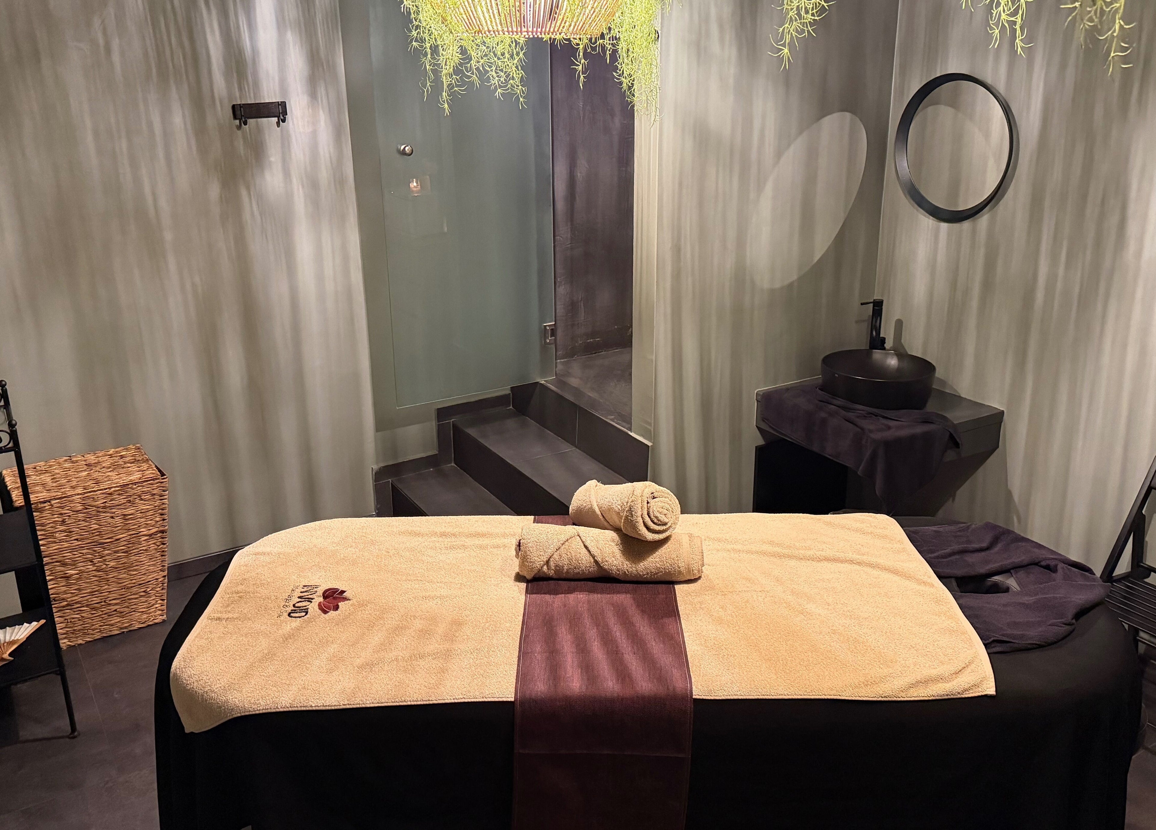 Χαλαρωτική αίθουσα μασάζ στο Invoid Spa, Peristeri, GR με κρεβάτι θεραπείας και διακοσμητικά στοιχεία.