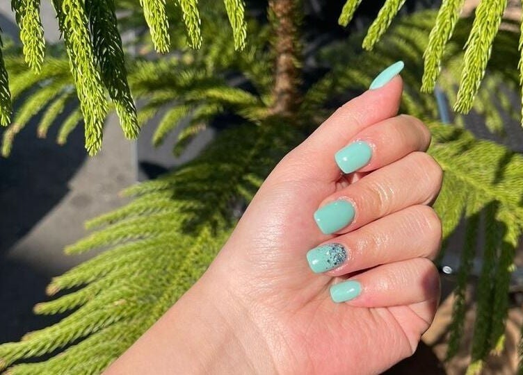 Mint green nails at Nice Nails and Wellness, Johannesburg, Gauteng, ZA, with lush green background.