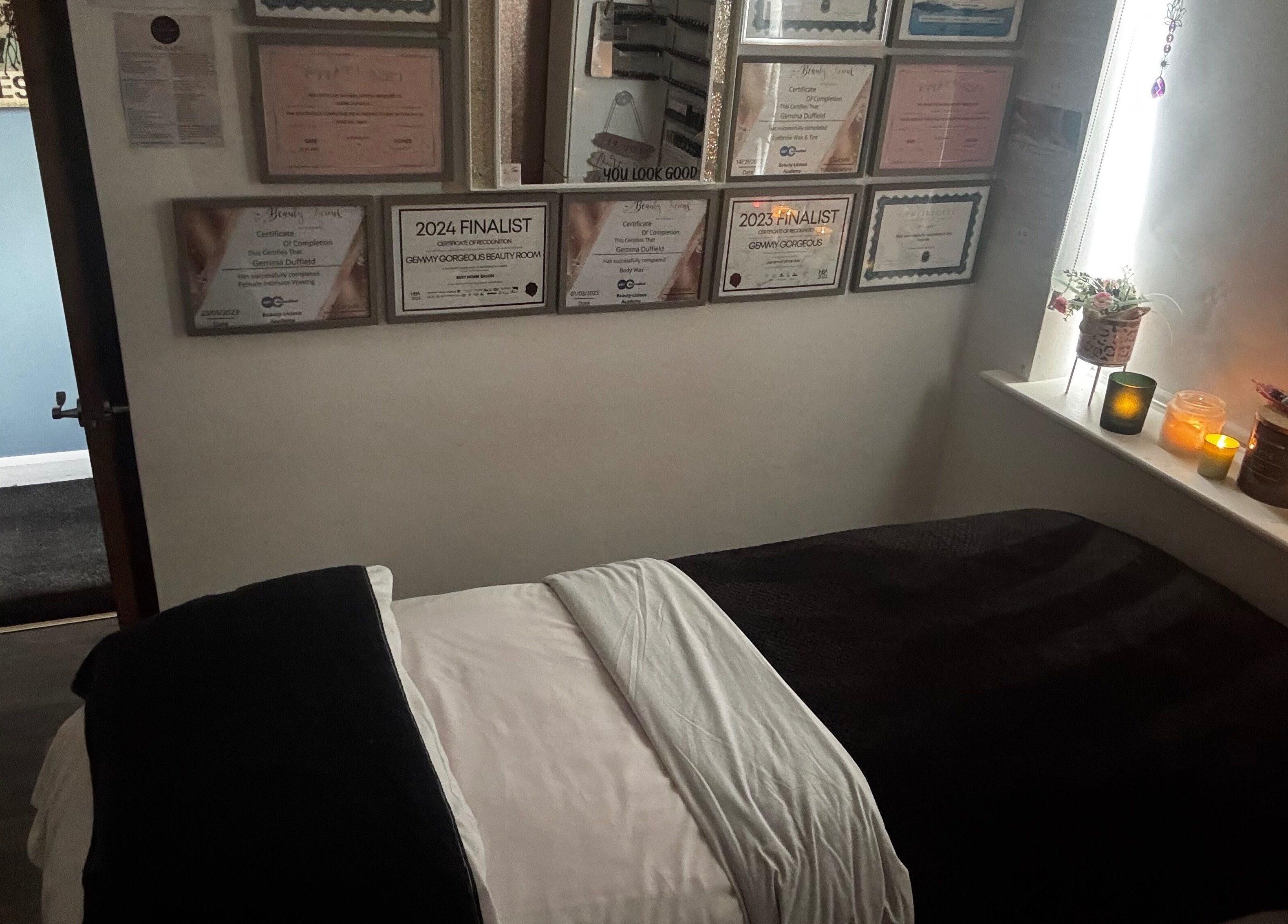 Relaxing treatment room at Gemmy Gorgeous, Leeds, England, GB with candles and certificates on display.