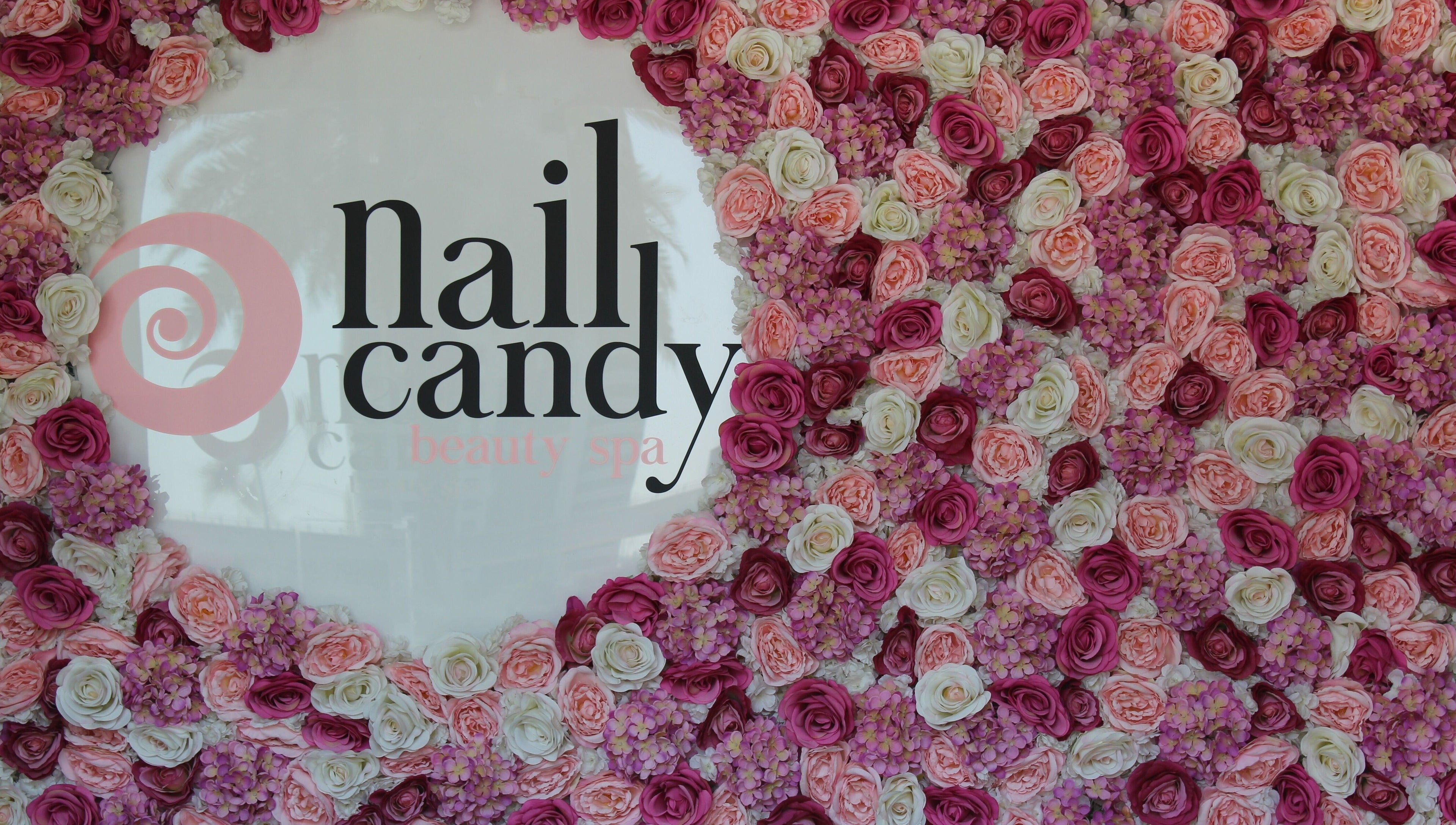 Flower-adorned wall with Nail Candy logo at Dubai, Dubai, AE, exuding elegance and charm.