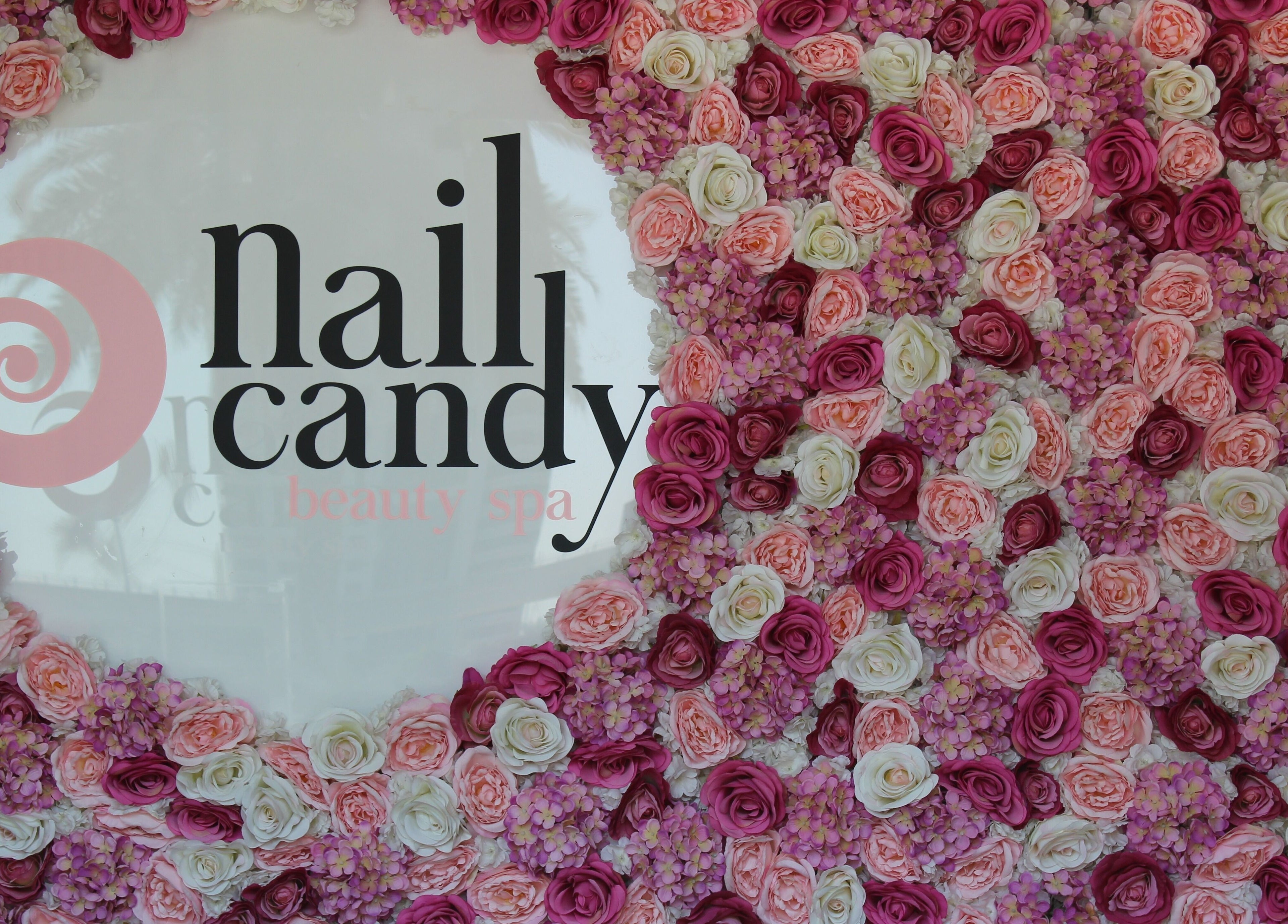 Flower-adorned wall with Nail Candy logo at Dubai, Dubai, AE, exuding elegance and charm.