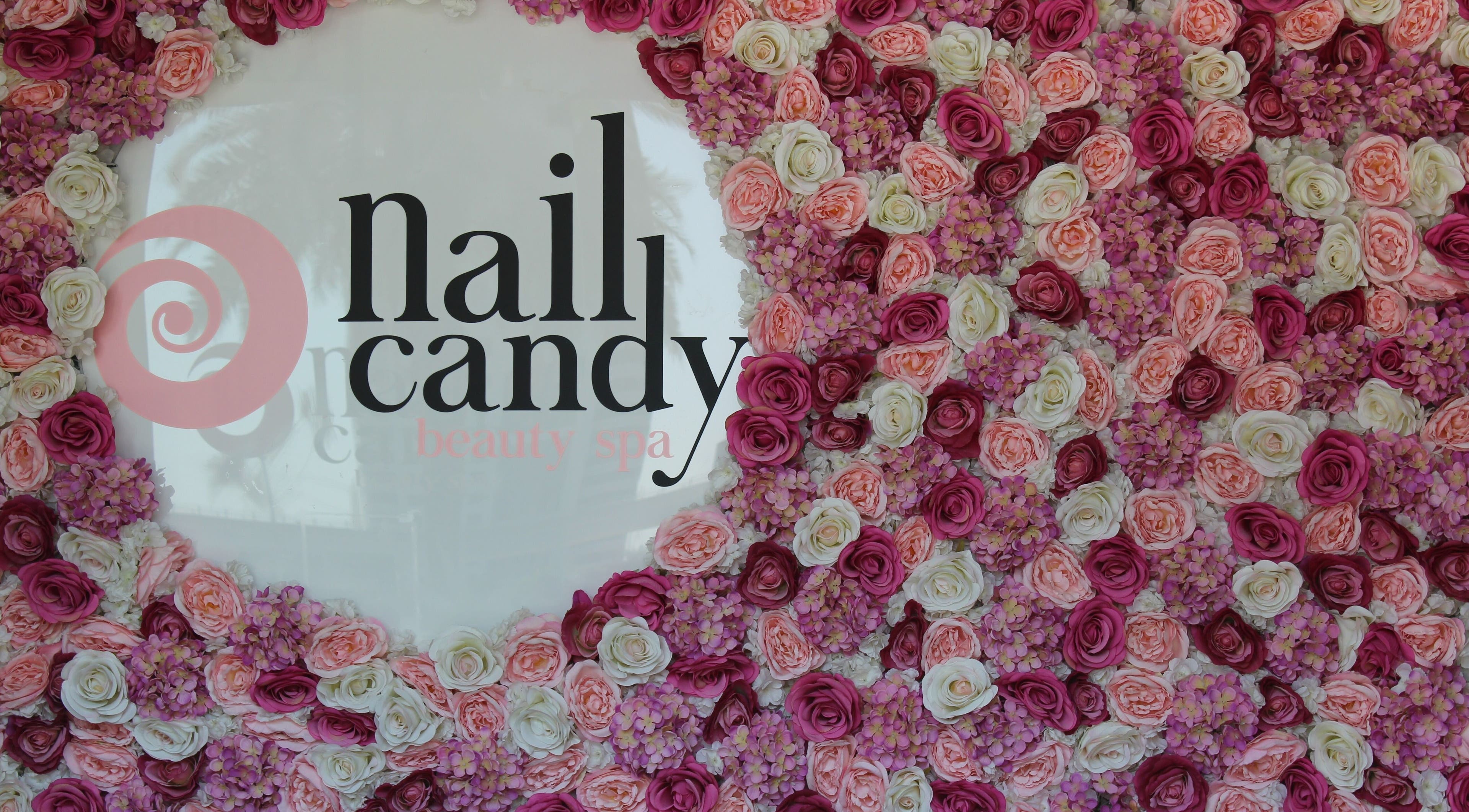 Flower-adorned wall with Nail Candy logo at Dubai, Dubai, AE, exuding elegance and charm.
