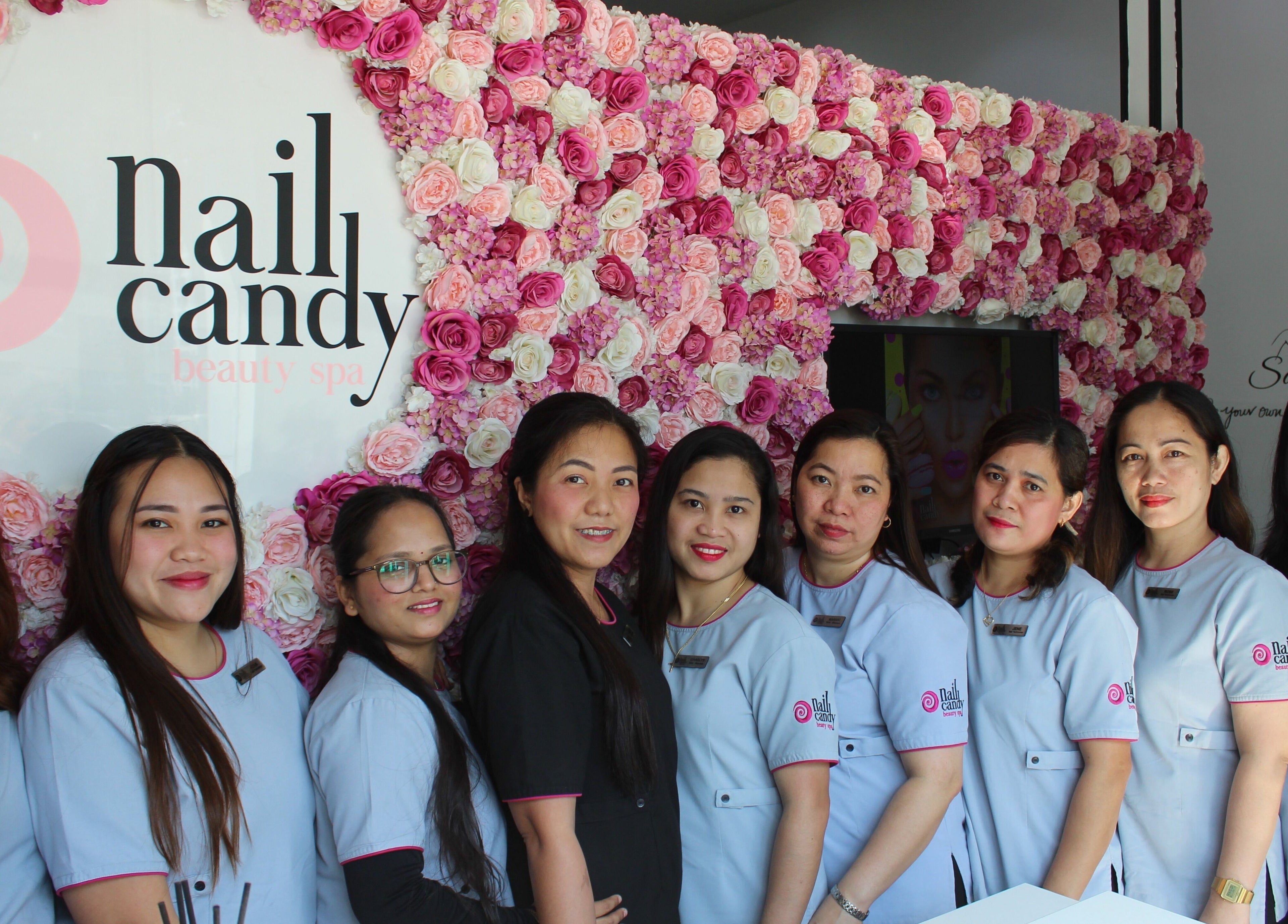 Team of stylists at Nail Candy, Dubai, Dubai, AE, in front of a floral wall.