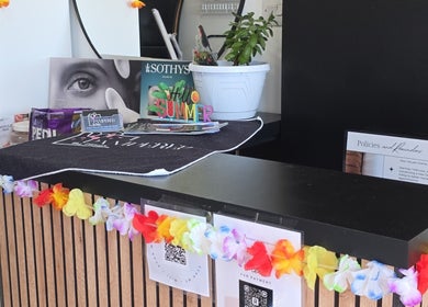 Reception desk at Pampered by Maya, L-imqabba, MT, decorated with colorful garlands and beauty products.