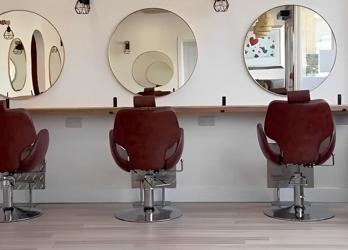 Three salon chairs facing large round mirrors at Omor Studio, Wetherby, England, GB.