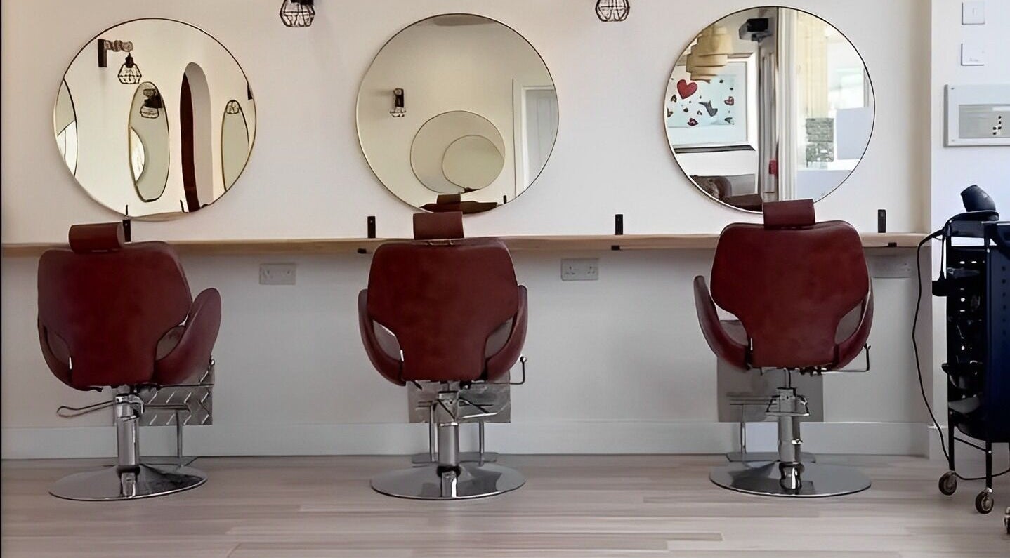 Three salon chairs facing large round mirrors at Omor Studio, Wetherby, England, GB.
